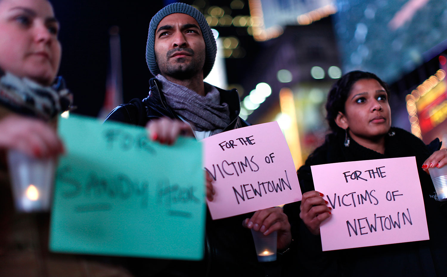 image: People hold a candlelight vigil in Times Square, for the victims of the Sandy Hook School shooting, in New York