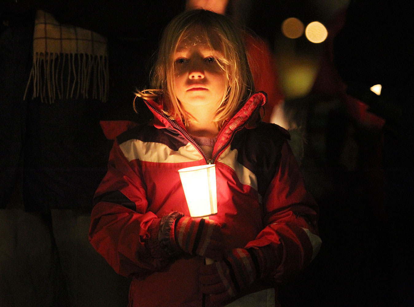 image: Noble holds a candle while attending a vigil for victims of a Connecticut school shooting, in Seattle