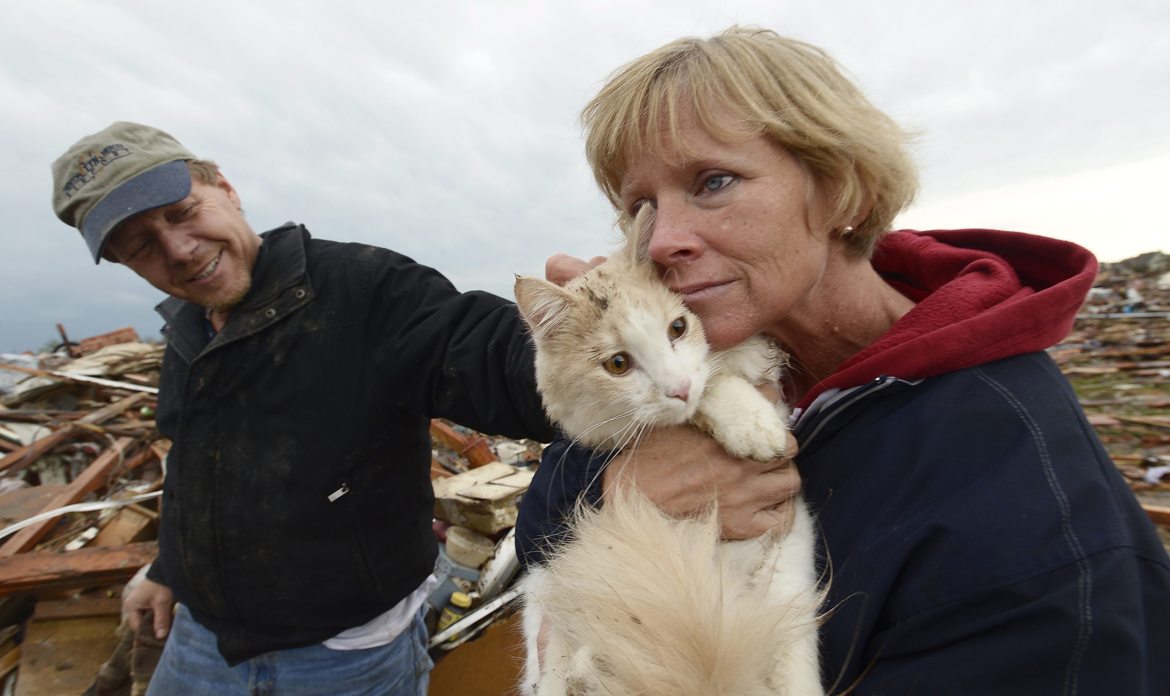 From left: Eric and June Simson hold their cat 'Sammi' seconds after finding it in the rubble of their home in a destroyed neighborhood in Moore, Okla., May 21, 2013.
