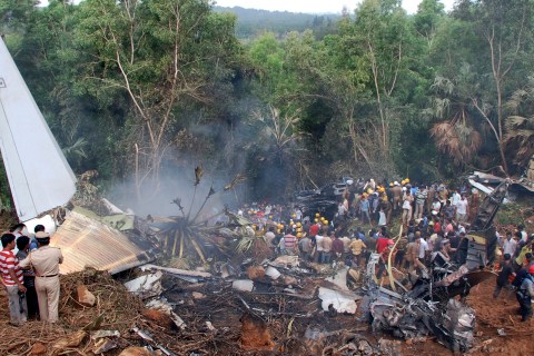 Onlookers and firefighters stand at the site of a crashed Air India Express passenger plane in Mangalore