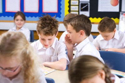 School boys whispering secrets in classroom