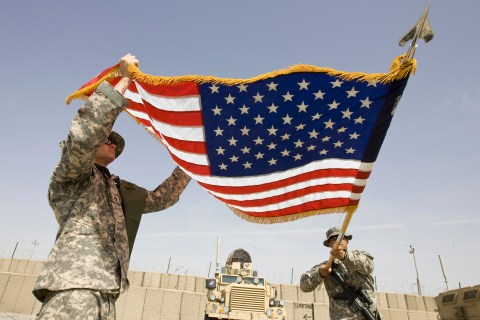 U.S. Army soldiers roll up a national flag after their headquarters' change of command ceremony at FOB Walton in Kandahar