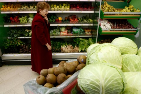 A woman walks inside a grocery store on the first day of the implementation of tax increases in Athens
