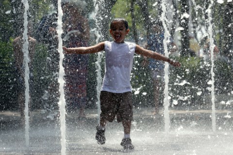 A boy plays at a fountain in Battery Park in New York