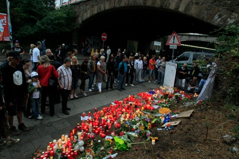 Mourners stand in front of a sea of candles and flowers at a tunnel in Duisburg