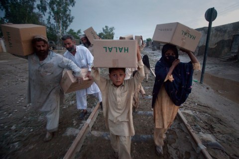 A family carries relief supplies, distributed by the Army, on train tracks back to their homes after flood waters receded in Nowshera