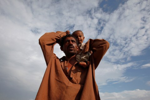 Flood victim carries his baby boy on his shoulder while taking refuge on a roadside makeshift relief camp in Sukkur