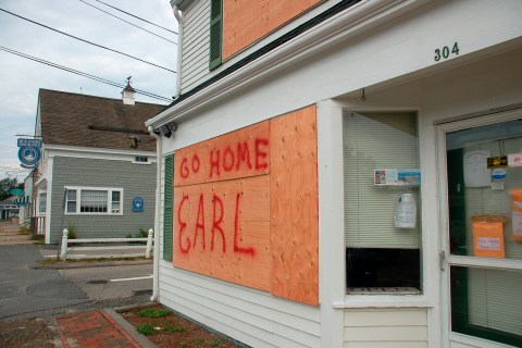 The windows of Cranberry Real Estate are boarded up and marked with a message to the looming storm in West Dennis