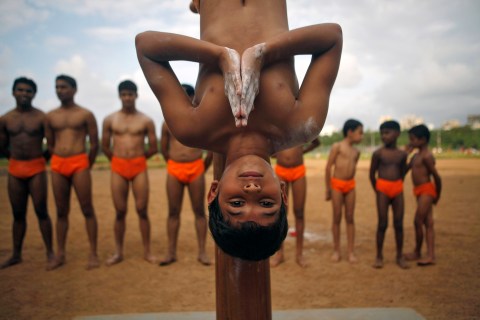 A boy performs Mallakhamb (gymnast's pole) during a practice session at a playground in Mumbai