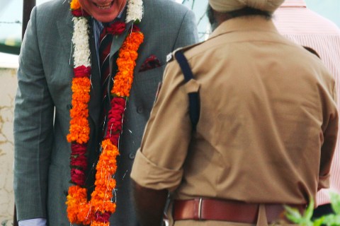 Britain's Prince Charles, wearing a garland, smiles during his visit to Hansali village in the northern Indian state of Punjab