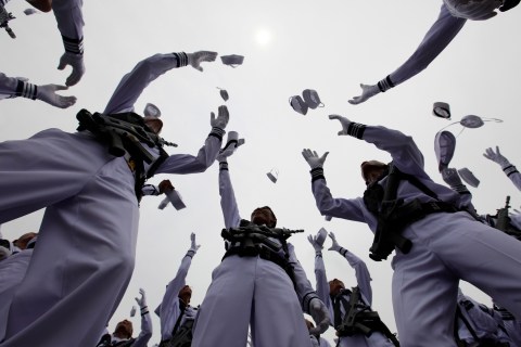 Indonesia's Navy servicemen throw their hats into the air to celebrate the 65th anniversary of the Indonesia National Military in Jakarta