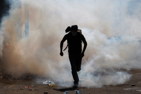 A protester runs through a cloud of tear gas in Umm el-Fahm