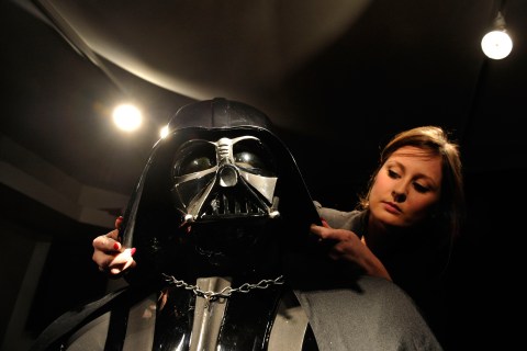 An employee adjusts the helmet on a rare Darth Vader costume at Christie's auction house in London