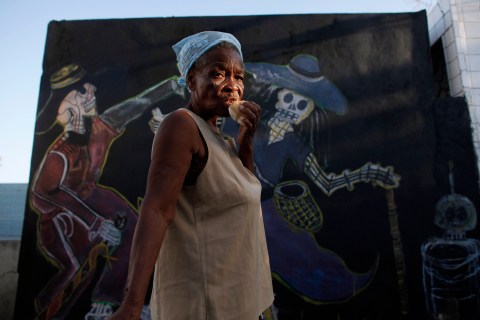 A Haitian voodoo practitioner eats bread during a ceremony at the national cemetery in Port-au-Prince