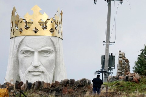 A man stands near the crowned head of a statue of Jesus being built in Swiebodzin