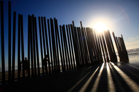 People stand at a wall separating Mexico and the United States in Tijuana as photographed from Imperial Beach
