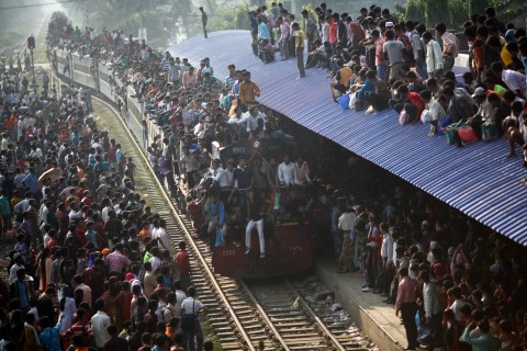An overcrowded train approaches as other passengers wait to board at a railway station in Dhaka