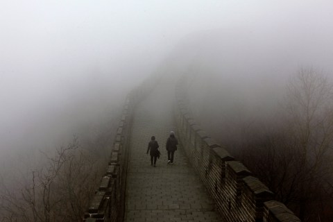 Tourists walk along a section of the Great Wall shrouded in mist at Simatai, located in the outskirts of Beijing