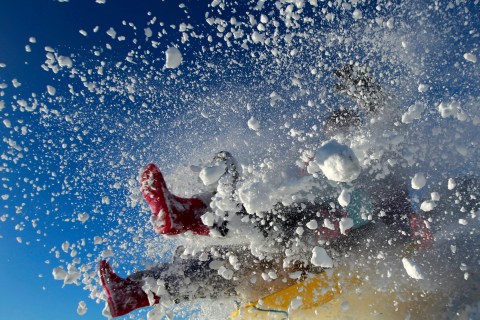 A sledger's boots are visible in an explosion of snow during an attempt to jump a ramp at the Queen Elizabeth country park