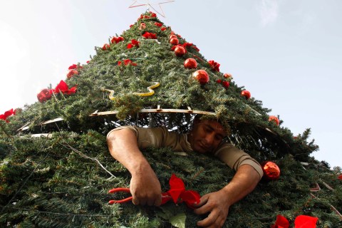 A worker adjusts ornaments on a Christmas tree that was erected in Sidon, southern Lebanon