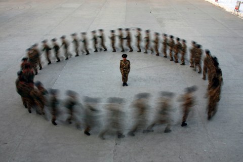 A commander watches as recruits of paramilitary police run in a circle during a training at a military base in Hami