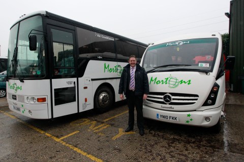 Adrian Morton, the owner of Mortons Travel, poses by two of his coaches