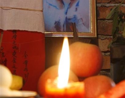A candle burns at a shrine in the home of Zhao Deqin for her twin daughters that died during last month's earthquake in Juyuan