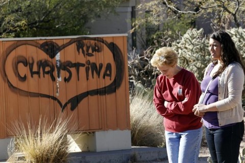 Woman stand near sign before funeral for Christina Green in Tucson