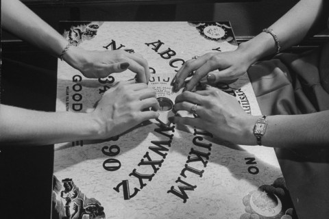 People playing with a Ouija Board.  