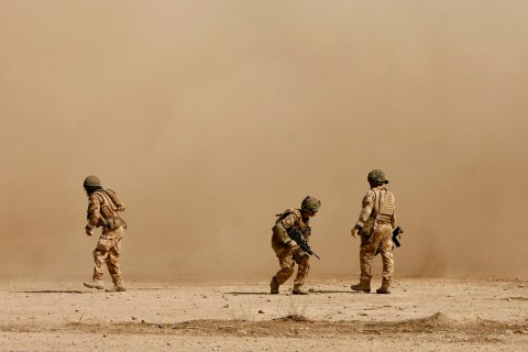 British soldiers cover themselves from dust as a helicopter lands at the Malgeer village in Helmand province