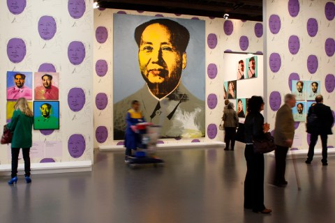 Visitors look at Mao paintings by US artist Andy Warhol during the exhibition "Le grand Monde d'Andy Warhol" at the Grand Palais museum in Paris