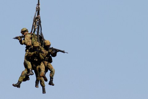 Members of Japan's Ground Self-Defense Force are carried by a rope from a helicopter at an annual military exercise in Funabashi