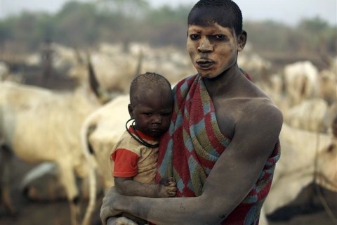 A man from the cattle herding Mundari tribe holds his son in a settlement near Terekeka