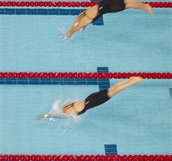 Competitors dive into the pool at the start of the women's 50m freestyle semi-finals at the Singapore