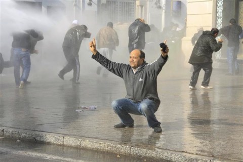A demonstrator reacts as security forces use water canons to disperse protesters in downtown Tunis