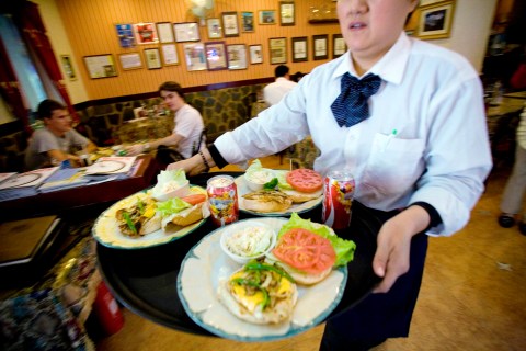 A waitress carries a tray of hamburgers at Steak & Eggs, a W