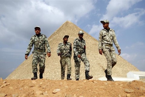 Egyptian soldiers walk in front of the Great Giza pyramids on the outskirts of Cairo