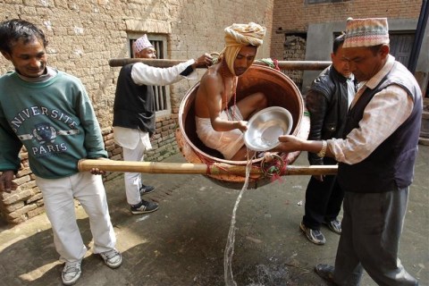 A devotee offers water to a man portraying God Madhavnarayan in Thecho near Kathmandu during the Madhav Narayan Mela