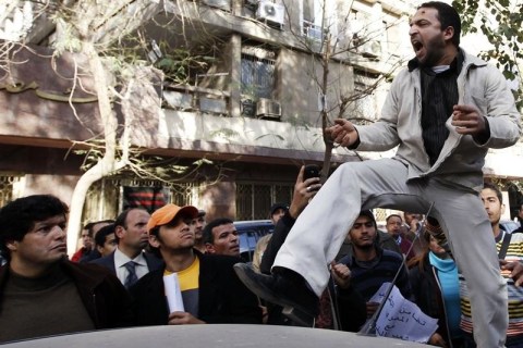 A Libyan protester stands on a car and shouts slogans against Libyan leader Muammar Gaddafi during a demonstration outside the Libyan Embassy in Cairo