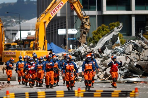 Japanese rescue workers walk past the rubble of the CTV building in Christchurch