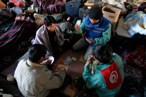 Vietnamese men play cards in a shed as they wait for transportation at the Libyan and Tunisian border crossing of Ras Jdir after fleeing unrest in Libya