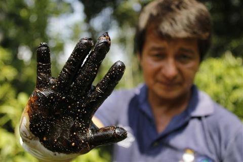 Environmentalist Donald Moncayo shows his glove after conducting a test made on an affected field in Lago Agrio January 25, 2011. 
