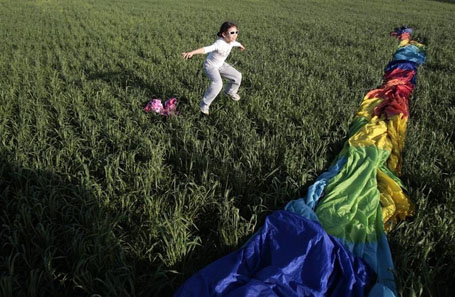 A girl jumps near a hot air balloon in a field in southern Israel
