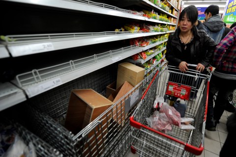 Shoppers look at empty shelves at a supe