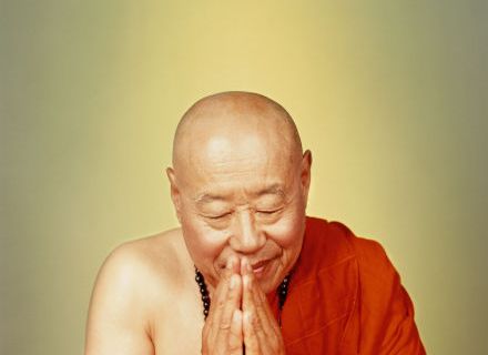 Buddhist monk in orange robe praying