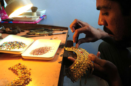 A Pakistani worker prepares a necklace a