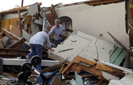 Larry Knoblauch helps his wife Evelyn as they climb through the wreckage of what was once their children's home in Joplin