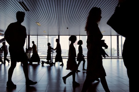 Silhouettes of travellers passing at an airport.
