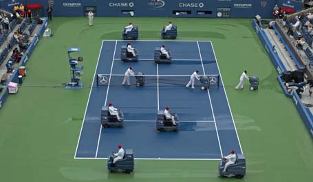 Court workers riding blower machines remove water from the playing surface of Arthur Ashe Stadium after rain delayed competition in the U.S. Open tennis tournament in New York