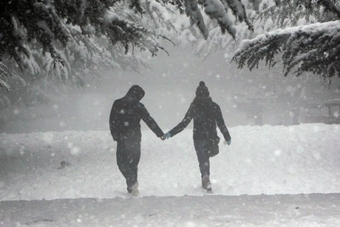 A couple walk during a snowfall in an amusement park in Tbilisi